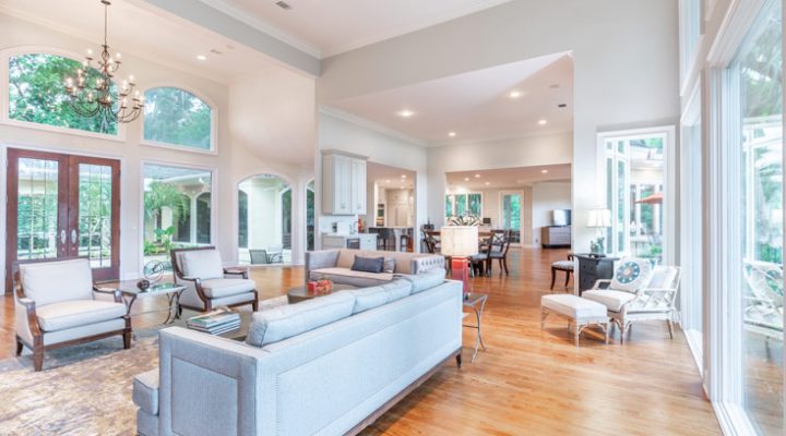 The large room has a big white couch and single couches scattered around it, and a chandelier hangs from the ceiling.