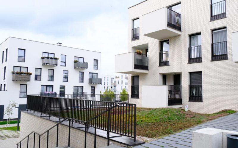 The outer walls of an apartment complex are painted white and have glass windows